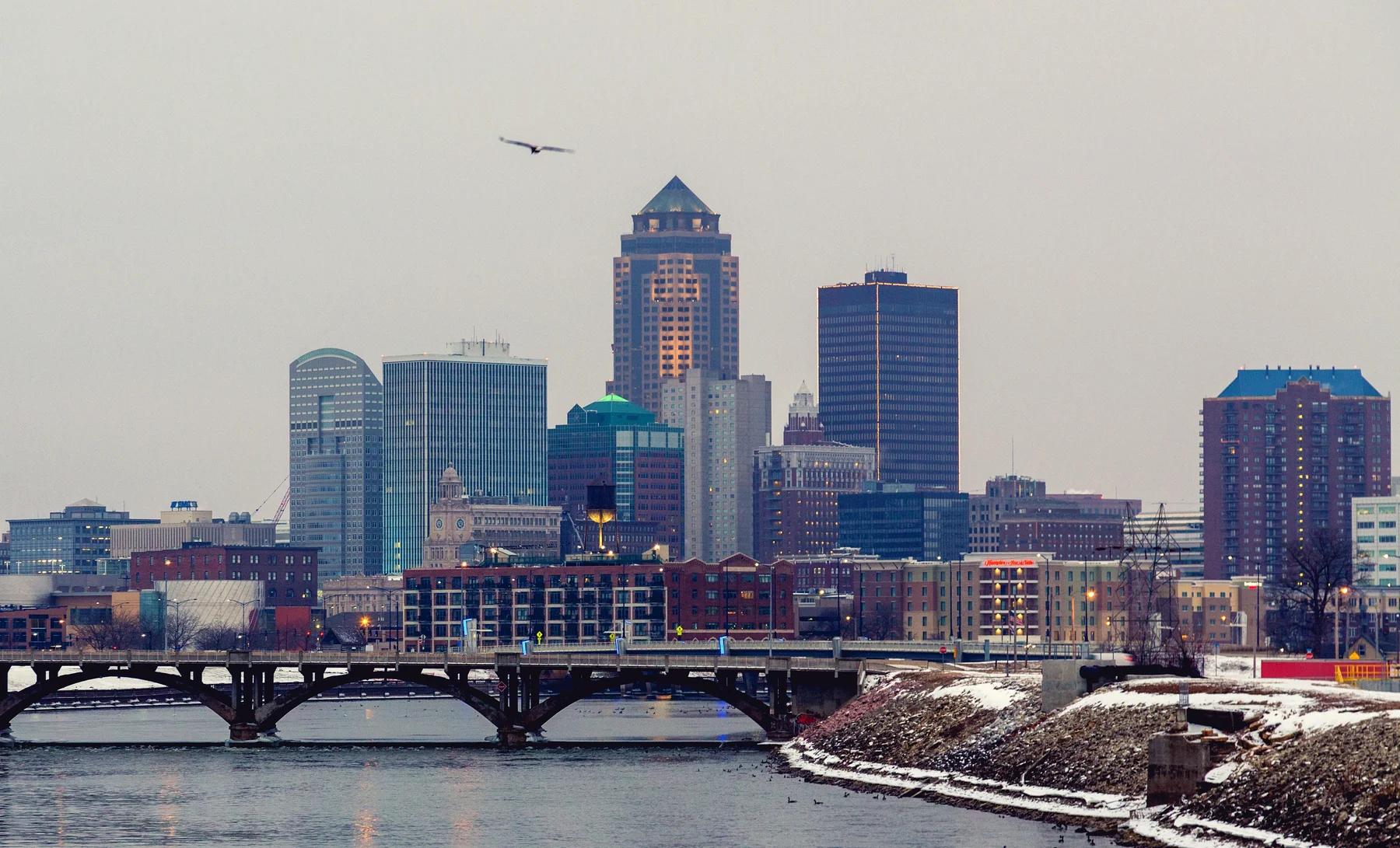 Downtown Des Moines skyline, a river bridge and snow-covered riverbank on a winter morning